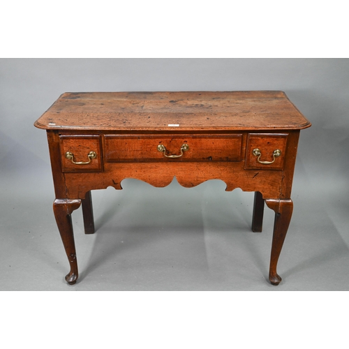 730 - An 18th century oak three drawer lowboy within a shaped apron, raised on cabriole legs to pad feet, ... 