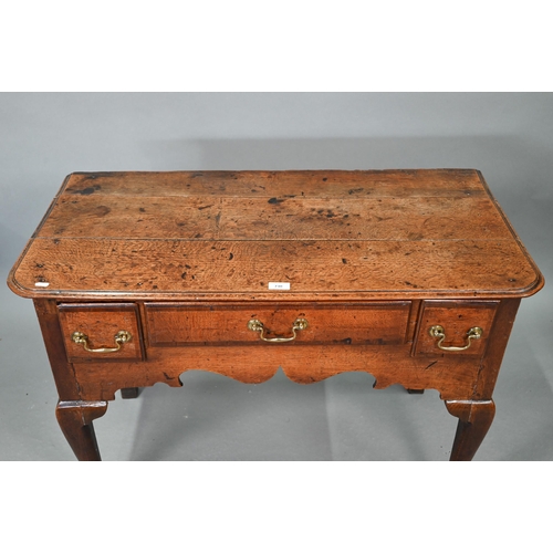 730 - An 18th century oak three drawer lowboy within a shaped apron, raised on cabriole legs to pad feet, ... 