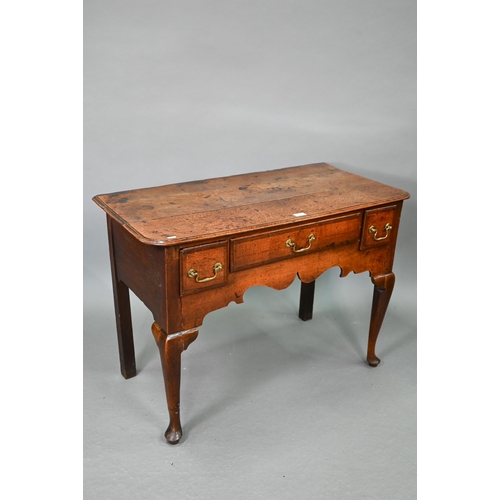 730 - An 18th century oak three drawer lowboy within a shaped apron, raised on cabriole legs to pad feet, ... 