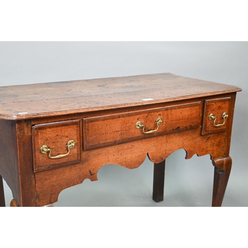 730 - An 18th century oak three drawer lowboy within a shaped apron, raised on cabriole legs to pad feet, ... 