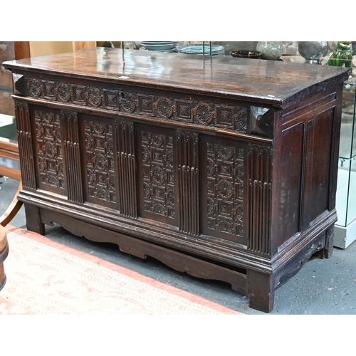 734 - An early 18th century oak coffer, the wide two plank staple hinged top over an ornate relief carved ... 