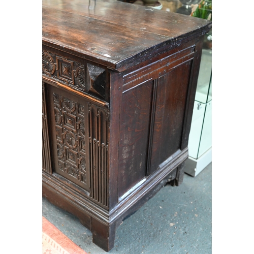 734 - An early 18th century oak coffer, the wide two plank staple hinged top over an ornate relief carved ... 