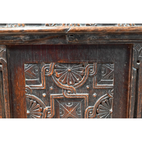 734 - An early 18th century oak coffer, the wide two plank staple hinged top over an ornate relief carved ... 