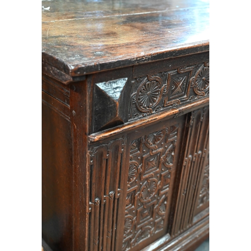 734 - An early 18th century oak coffer, the wide two plank staple hinged top over an ornate relief carved ... 