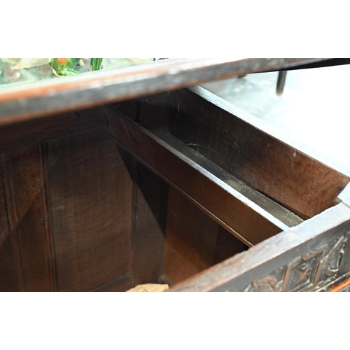 734 - An early 18th century oak coffer, the wide two plank staple hinged top over an ornate relief carved ... 