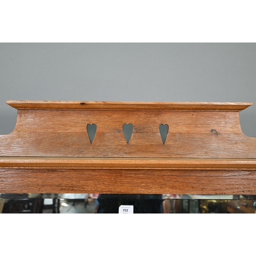 752 - An early 20th century Arts & Crafts mirror backed oak sideboard, the bevel edged plate flanked b... 