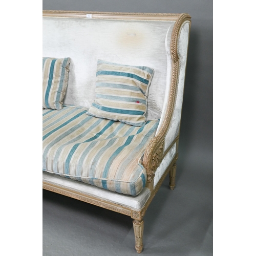 754 - A French Empire style two seater sofa, the carved and moulded frame washed off-white, having a fabri... 