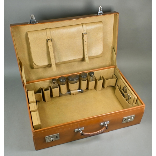 919 - A 1930s pigskin suitcase with fittings including six silver-topped glass jars and bottles, London 19... 