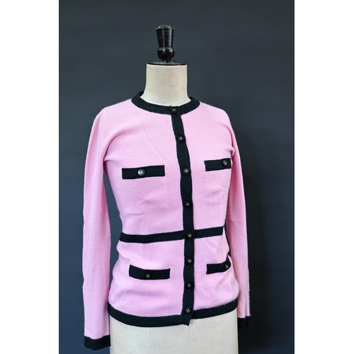 932 - Chanel - A long fitted pink cashmere cardigan with black trim and black and gilt Chanel motif button... 