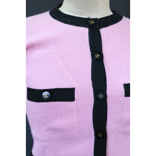 932 - Chanel - A long fitted pink cashmere cardigan with black trim and black and gilt Chanel motif button... 