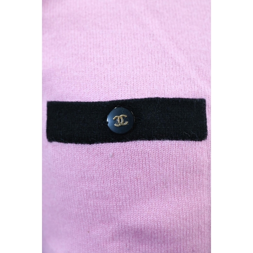 932 - Chanel - A long fitted pink cashmere cardigan with black trim and black and gilt Chanel motif button... 