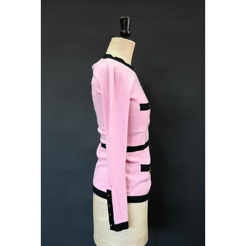 932 - Chanel - A long fitted pink cashmere cardigan with black trim and black and gilt Chanel motif button... 