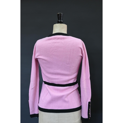 932 - Chanel - A long fitted pink cashmere cardigan with black trim and black and gilt Chanel motif button... 