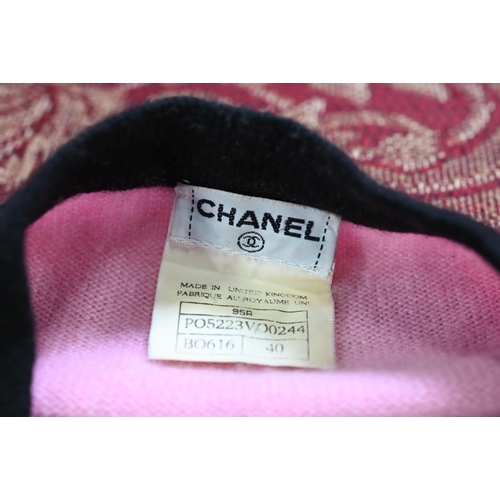 932 - Chanel - A long fitted pink cashmere cardigan with black trim and black and gilt Chanel motif button... 