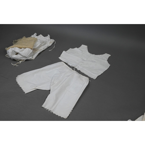 943 - Two antique child's cotton gowns, a woollen lacy shawl and a quantity of antique undergarments withi... 