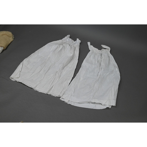 943 - Two antique child's cotton gowns, a woollen lacy shawl and a quantity of antique undergarments withi... 