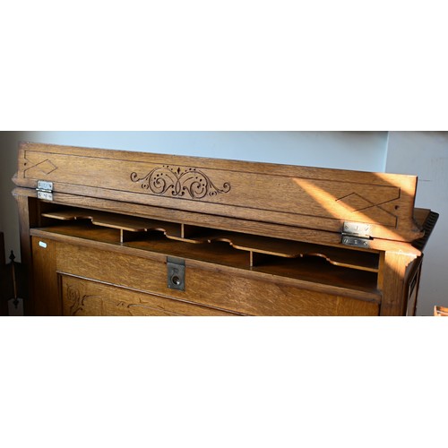 707 - An antique American Wells Fargo 'Wooton' style desk, golden oak, the hinged upper panel over a pair ... 