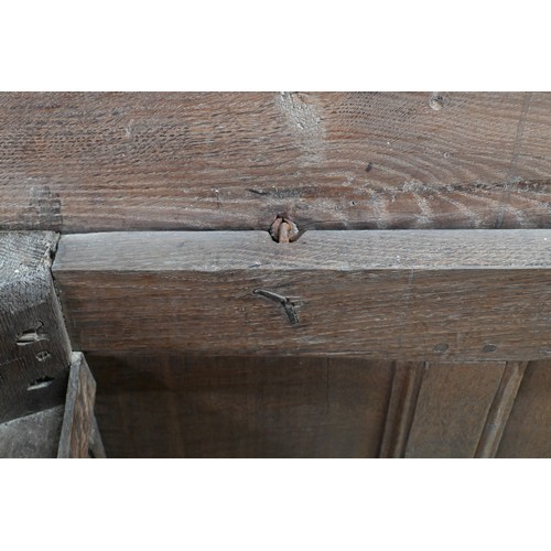 734 - An early 18th century oak coffer, the wide two plank staple hinged top over an ornate relief carved ... 