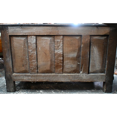 734 - An early 18th century oak coffer, the wide two plank staple hinged top over an ornate relief carved ... 