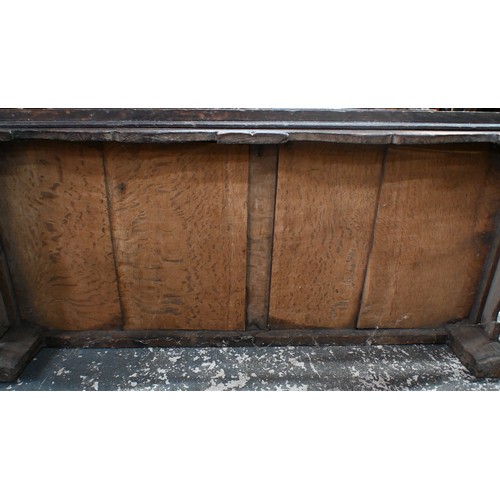734 - An early 18th century oak coffer, the wide two plank staple hinged top over an ornate relief carved ... 
