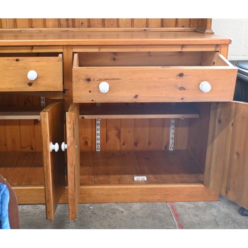 51 - A heavy quality stained pine kitchen dresser with plate rack above two frieze drawers and four panel... 