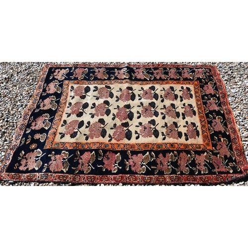 97 - An old Persian camel ground rug with repeat stylised rose design, 152 cm x 106 cm