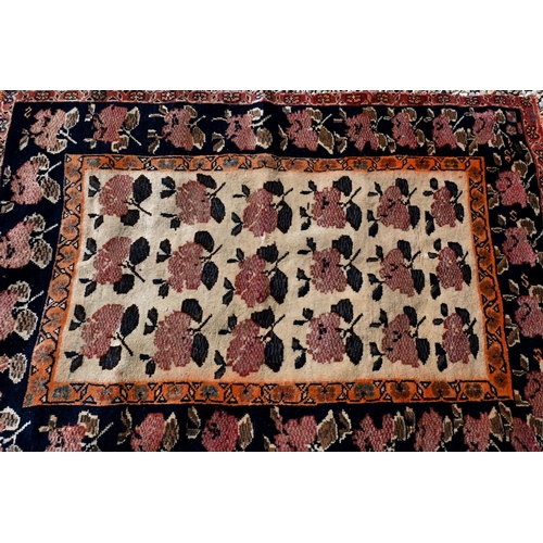 97 - An old Persian camel ground rug with repeat stylised rose design, 152 cm x 106 cm