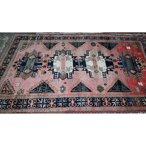 186 - A mid-century Turkish rug, the faded red ground rug with geometric design, 228 cm x 164 cm