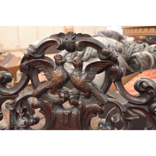 117 - A Continental oak high backed hall chair profusely carved foliate frame, the crest carved with two b... 