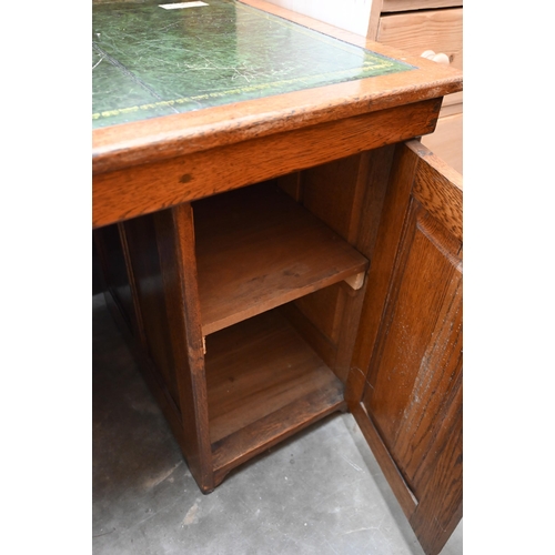 13 - An oak kneehole desk with gilt-tooled green leather top over four drawers (left) and panelled cupboa... 