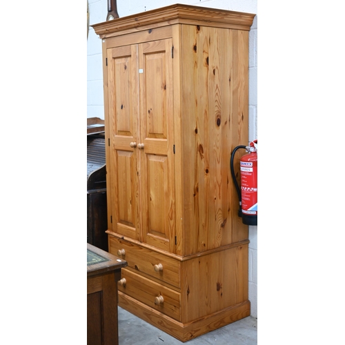 14 - A stained pine wardrobe with panelled doors enclosing hanging rail, on base with two drawers, 92 x 6... 