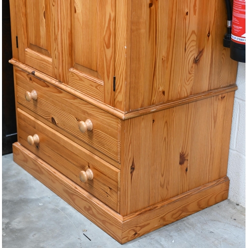 14 - A stained pine wardrobe with panelled doors enclosing hanging rail, on base with two drawers, 92 x 6... 