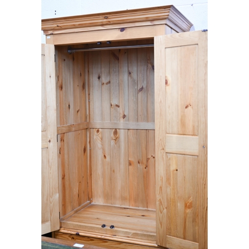 14 - A stained pine wardrobe with panelled doors enclosing hanging rail, on base with two drawers, 92 x 6... 