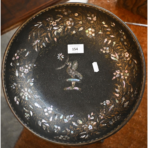 154 - A black papier-maché bowl with mother of pearl inlay on black painted tripod stand, 78 cm high