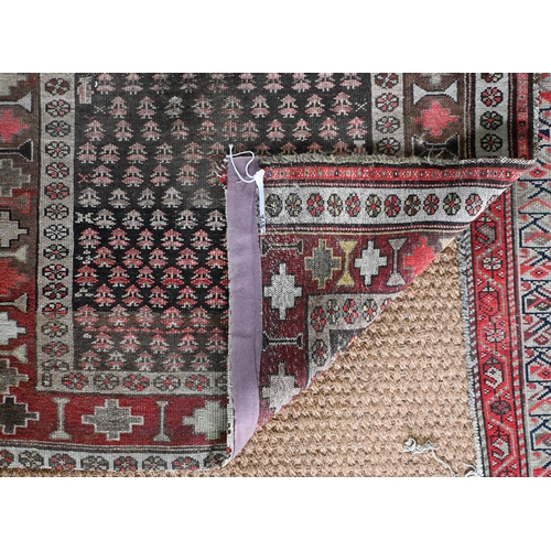 188 - A Kurdish repeat design rug, brown ground with geometric and floral borders, 216 cm x 105 cm