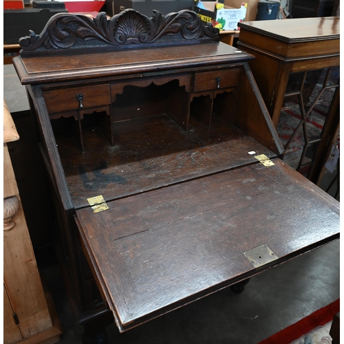 28 - A carved oak bureau with fall front panel enclosing fitted interior over three drawers on turned sup... 