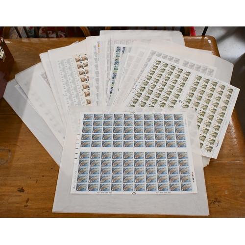 556 - A quantity of British postage stamp full sheets - mostly 1980s commemoratives, in folio case