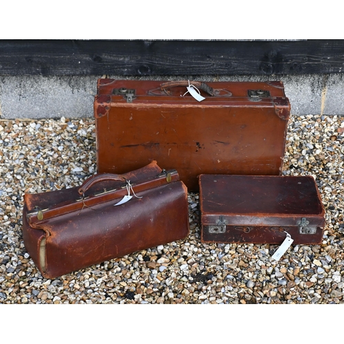 579 - An antique leather Gladstone bag and two vintage leather suitcases (3 - a/f)