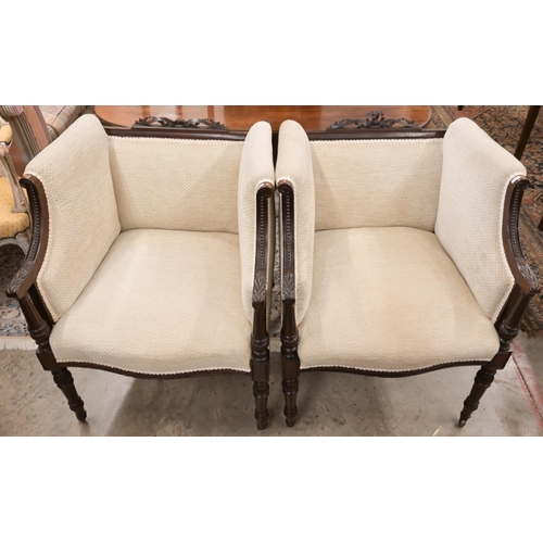 61 - A pair of carved mahogany ribbon crested salon armchairs in the Empire Style, with lattice stone fab... 