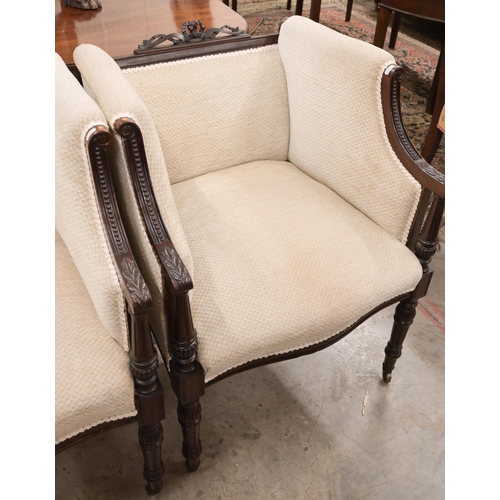 61 - A pair of carved mahogany ribbon crested salon armchairs in the Empire Style, with lattice stone fab... 