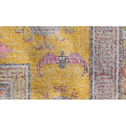 182 - A Chinese design very worn/faded yellow ground rug with bats and floral roundels scattered around ce... 