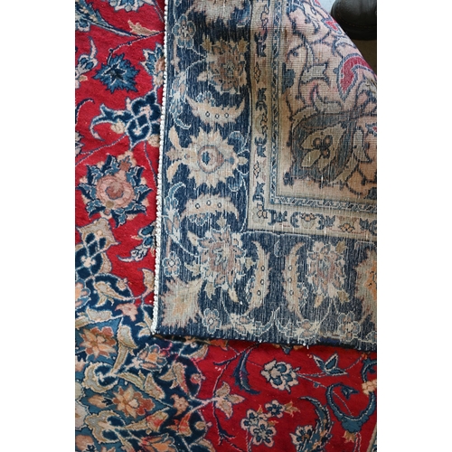 10 - A Persian Mashad carpet with traditional floral design on red ground, navy blue palmette pattern bor... 