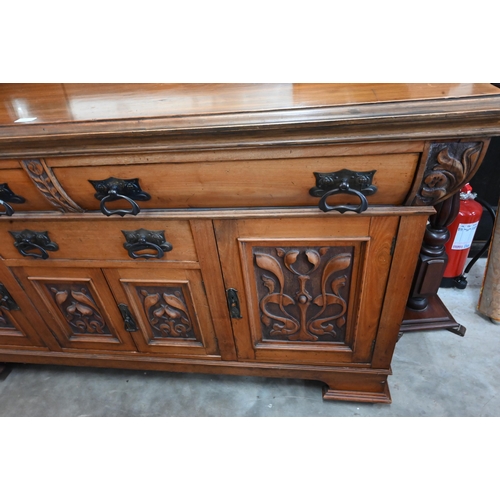 101 - A substantial Art Nouveau carved walnut mirror-backed sideboard with bevelled plate between turned p... 