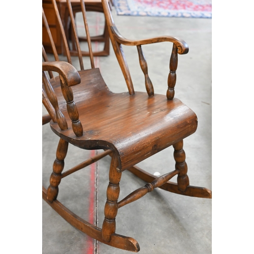 18 - A vintage Danish stained pine spindle back rocking chair with scroll seat and bobbin turned supports