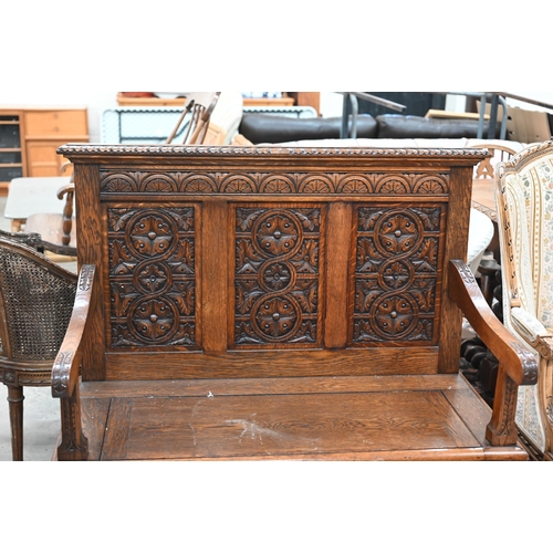 22 - An oak box seated settle with lunette foliate carved panels and hinged seat, 106 cm w x 46 cm d x 10... 