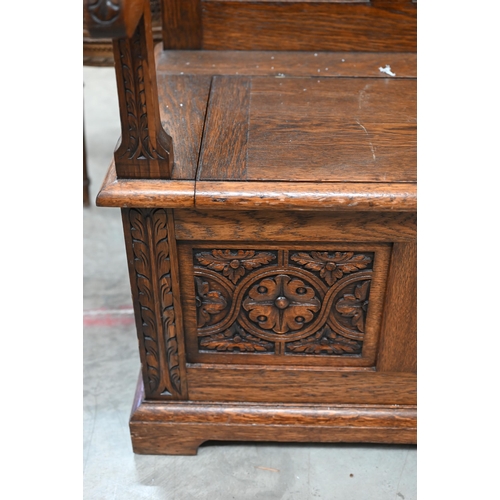 22 - An oak box seated settle with lunette foliate carved panels and hinged seat, 106 cm w x 46 cm d x 10... 