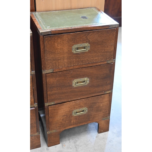 46 - A pair of campaign-style three drawer bedside chest with gilt tooled leather tops, brass mounts and ... 