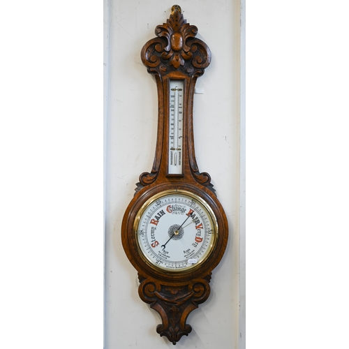 461 - # An antique carved oak banjo-cased aneroid barometer/thermometer 92cm high