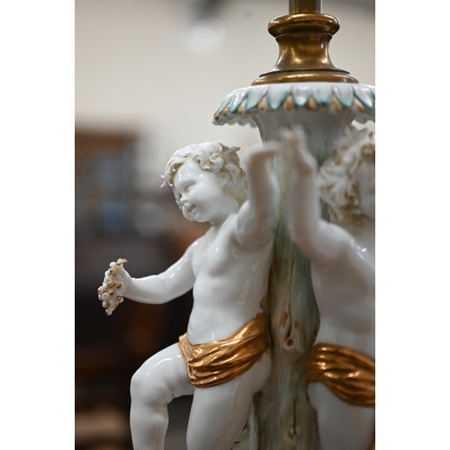 467 - An Italian white-glazed and gilded ceramic lamp modelled with three dancing putti, on brass base, 48... 