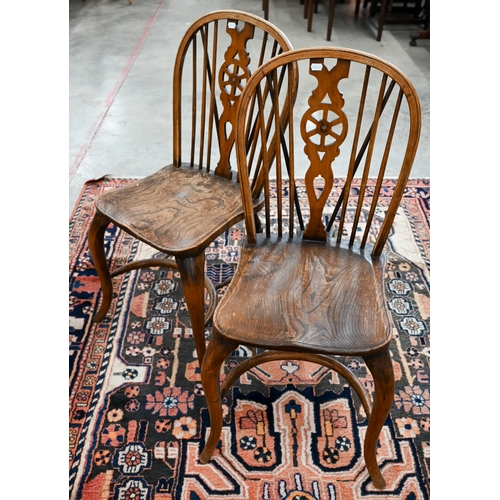 51 - A set of four provincial elm seated wheel back dining chairs with turned legs and crinoline front st... 